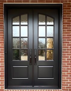 a black double door with two sidelights and brick wall in front of the house