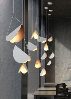 some lights hanging from the ceiling in a room with tables and chairs around them,