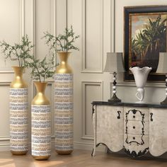 three vases sitting on top of a wooden floor next to a table with flowers in it