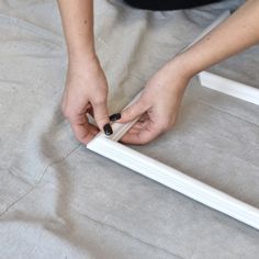 a woman is working on an unfinished piece of furniture with white paint and black nail polish