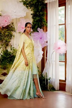 Feel the summer breeze in this flowy Zinnia Kaftan. It is beautifully adorned with floral motif embroidery all over, highlighted with golden and aqua-hued sequence work. To give it that elegant look, an ombre hue of aqua is added at the bottom of the Cape. To match the cape, A fully sequenced dress balances the sophistication and adds a modern touch to the outfit. This summer festive season, this flowy attire with pristine hues is the perfect choice to go with. Cape-style kaftan is covered with