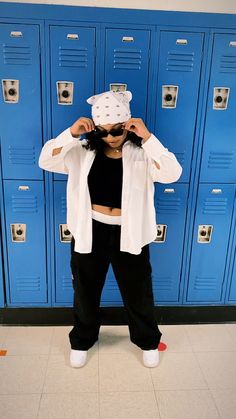 a woman standing in front of lockers with her hands on her head and wearing a white hat