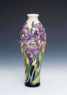 a vase with purple flowers painted on the side and green leaves in the bottom, against a gray background