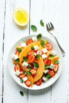 a white plate topped with fruit and feta cheese