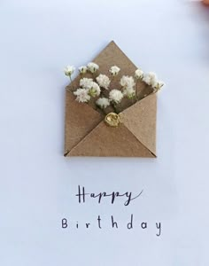 an envelope with flowers in it and the words happy birthday written on paper next to it