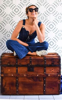 a woman sitting on top of a wooden trunk