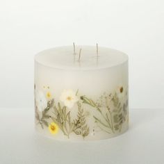 a white candle with yellow and white flowers on it