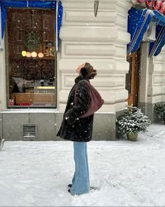 a woman standing in front of a store on a snowy day