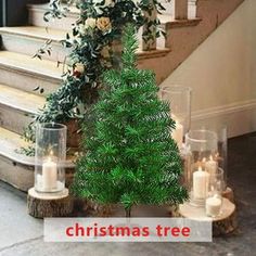 a small christmas tree sitting on top of a wooden table next to candles and flowers