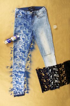 a pair of blue jeans with lace on them next to an empty can and fabric