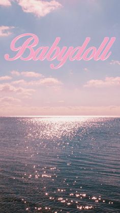 the words baby doll are written in pink and blue on top of an ocean view