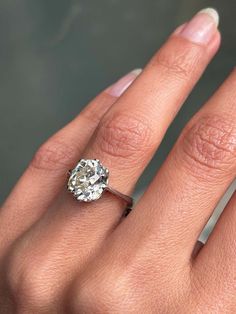 a woman's hand with a diamond ring on top of her finger and an engagement band