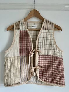 a vest hanging up on a wall with a wooden hanger in front of it