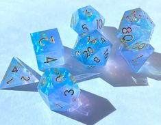 blue and white dice with gold numbers on them sitting in the middle of some snow