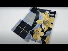 two napkins with yellow flowers on black and white checkered paper, one is folded to the side