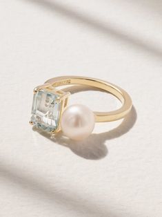 a gold ring with an aqua blue topazte and a white pearl in the middle