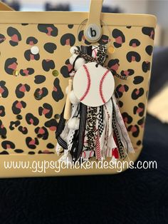 a keychain with a baseball on it sitting in front of a leopard print purse