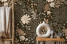 a table with a white vase on top of it next to a brown wallpaper