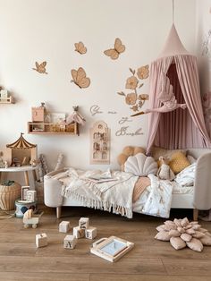 a child's bedroom decorated in pink and gold with butterflies on the wall above it