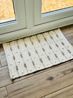 a white rug sitting on top of a wooden floor next to a window