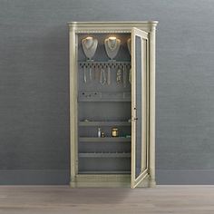 an open cabinet with silverware and glasses on the door is shown in front of a gray wall