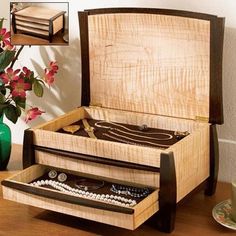 a wooden jewelry box sitting on top of a table next to a vase with flowers