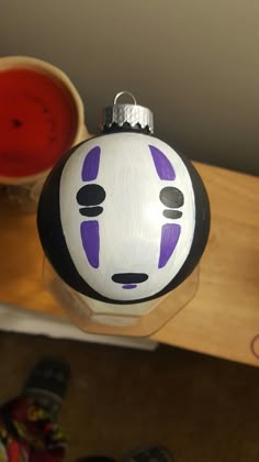 a white and purple ornament sitting on top of a wooden table next to a cup