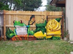 a painted fence with a yellow rose and a green frog