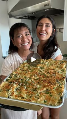 two women holding up a large casserole dish