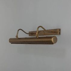 an antique brass wall light fixture with two arms and one arm holding a hook on the side