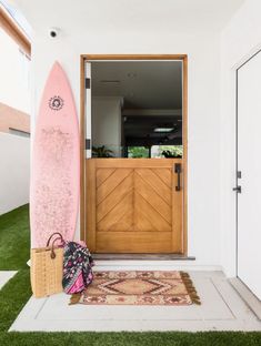 a pink surfboard sitting next to a wooden door