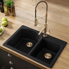 two black sinks sitting on top of a wooden counter next to green apples and bottles