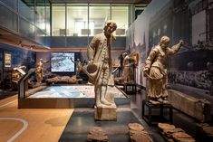 several statues in a museum with glass walls