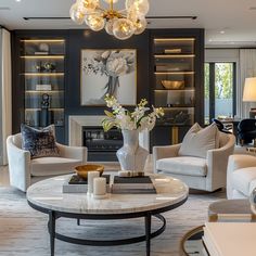 a living room filled with furniture and a chandelier hanging from the ceiling in front of a fire place