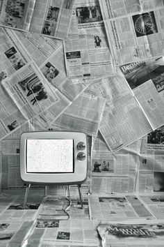 an old tv sitting on top of a table covered in newspaper pages and newspapers scattered around it