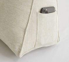 a close up of a cell phone in a pocket on a pillow with white linen