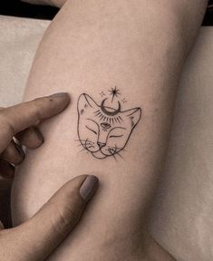 a woman's thigh with a tattoo of a cat and the moon on it