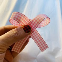 a hand holding a piece of paper with a red and black checkered ribbon on it