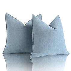 two blue pillows sitting next to each other