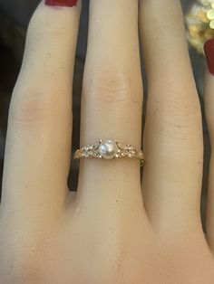 a woman's hand with a ring on it that has two pearls in the middle