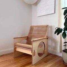 a wooden chair sitting on top of a hard wood floor next to a potted plant