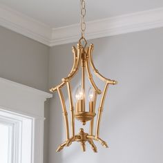 a golden chandelier hanging from the ceiling in a room with white walls and windows