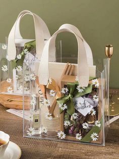 two clear bags with white flowers in them on a table next to a cup and saucer