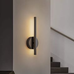 a wall light that is mounted on the side of a wall next to some stairs