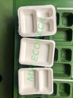 three plastic trays sitting next to each other on top of a green tablecloth