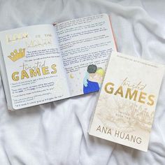 two books laying on top of a bed next to each other in front of a white sheet