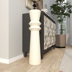 a tall white vase sitting on top of a hard wood floor next to a wall