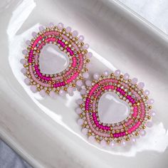 "These earrings are meticulously handcrafted with quality Japanese seed beads in various pinks with gold opal & gold AB rhinestone banding edged with pink glass beads and gold seed beads on a gold nickel-free stud post. Earring backing is faux leather. Earrings measure ~2\" in length and width." Glass Beaded Earrings, Fancy Shawl Regalia, Beaded Heart Earrings, Beaded Stud Earrings, Valentines Day Jewelry, Beaded Earrings Native, Beadwork Designs, Heart Earring, Native Beadwork