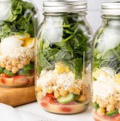 three mason jars filled with different types of salads and veggies in them