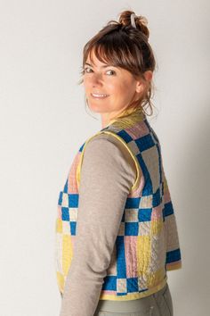 a woman is smiling while wearing a colorful sweater and skirt with her hair in a bun